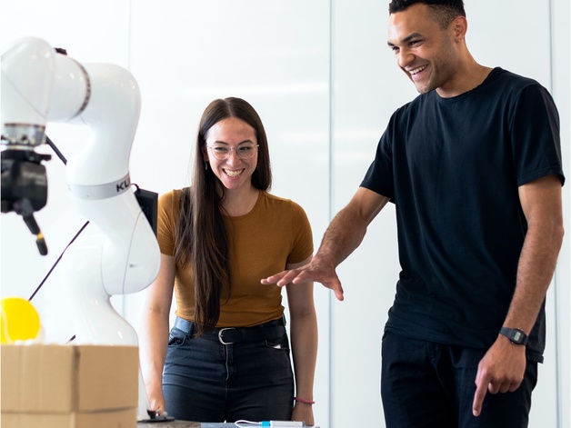 two people interacting with robot arm