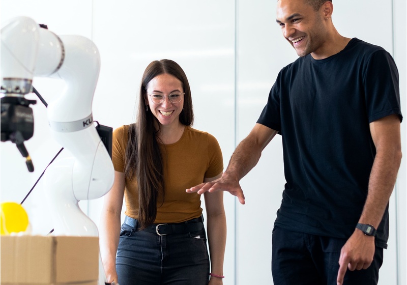 two people interacting with robot arm