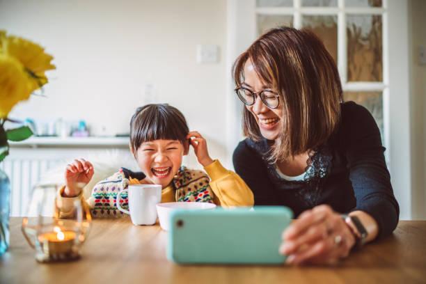 Parent and child laughing using mobile device